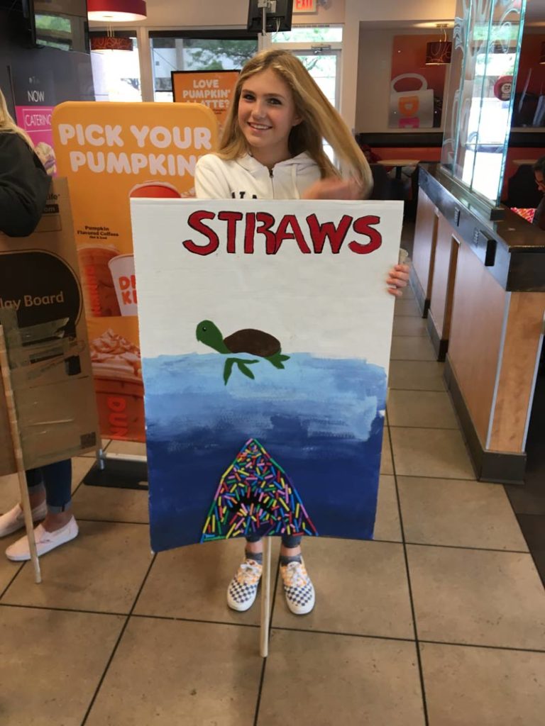 One of the posters at the student organized Climate Strike showing a turtle being pursued by a shark made out of plastic straws