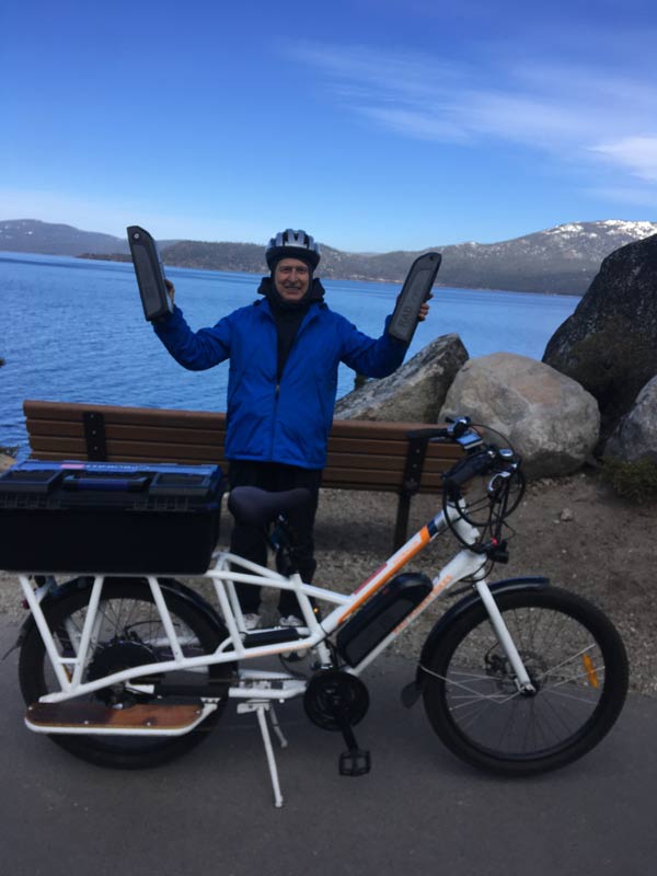 John holding up his two spare batteries in front of Sunride, Jr. with Lake Tahoe in the background.