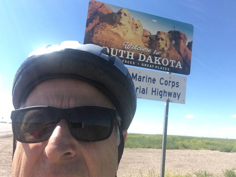 John taking a selfie in front of the South Dakota state line sign.