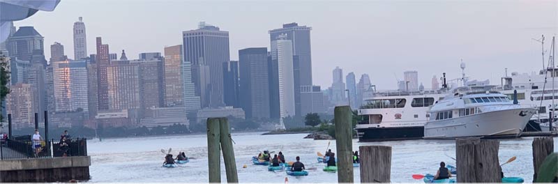 In the foreground kayakers on the Hudson make their way toward the city.