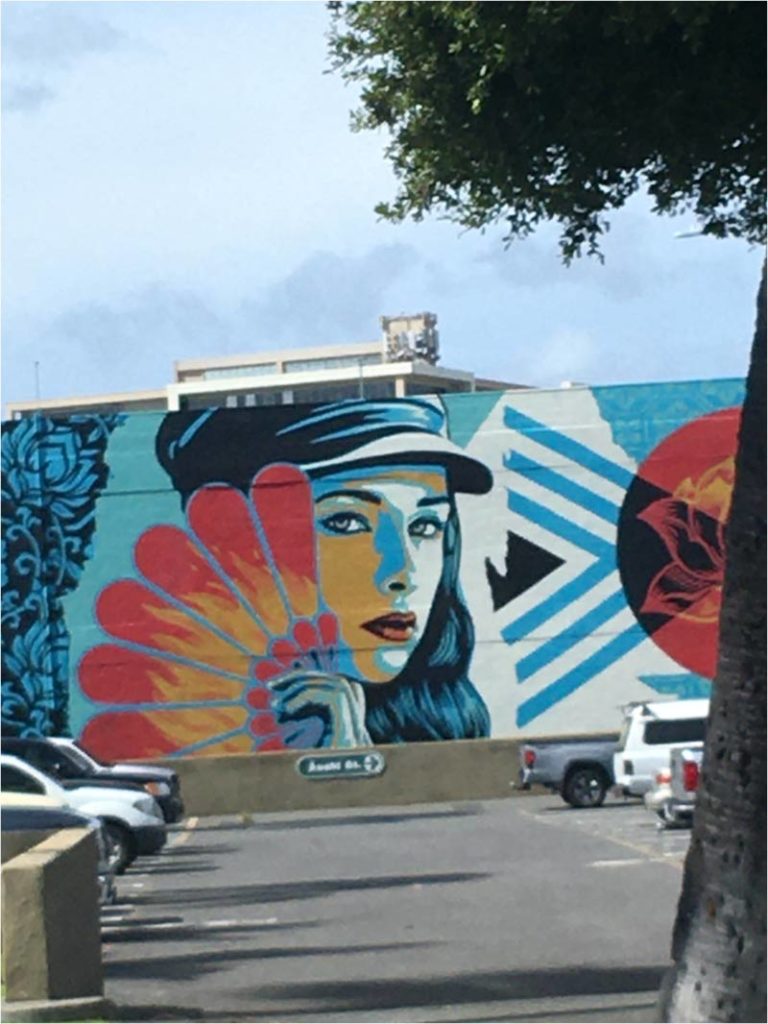 Mural of a beautiful, mysterious woman in a hat holding a fan