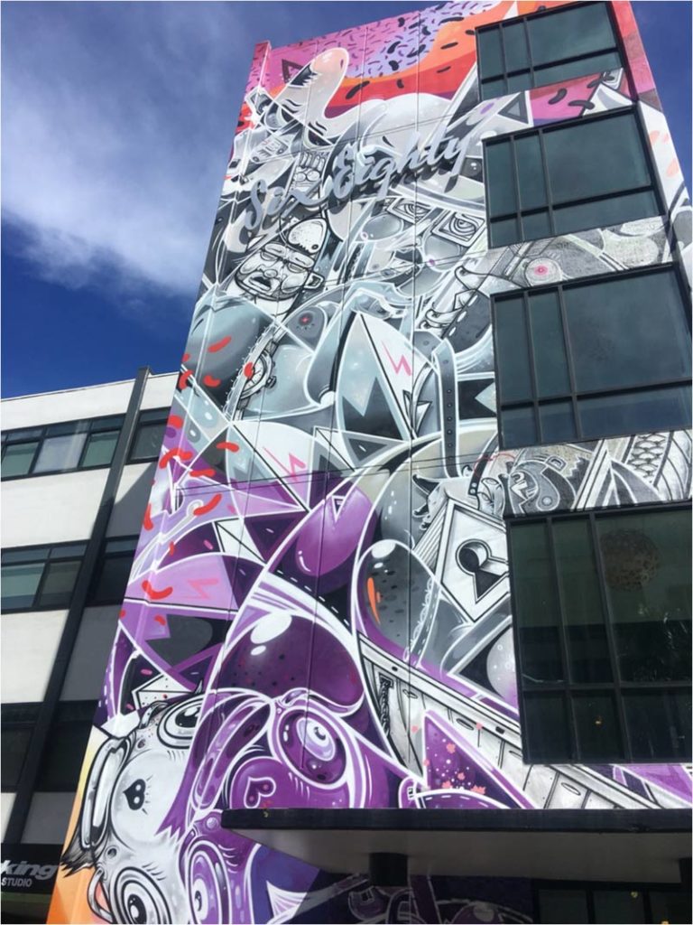 Modern art mosaic on a tall building with purple, silver and muted green accents